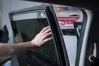 A person putting window tinting on a vehicle.