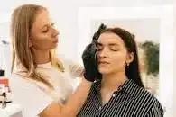 A mobile beauty therapist putting make up on a female client.