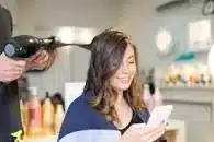 Person sitting in a chair having their hair done by a mobile hairdresser.