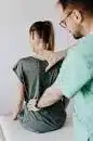 An osteopath checking a persons back.