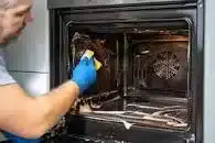 Aperson cleaning an oven.