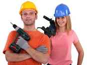 Tradespeople with helmets on and power drills in their hands.