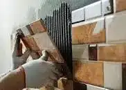 Tiler putting tiles on wall.