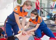 two people carrying out CPR on a dummy as part of first aid training.