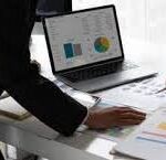 Business consultants looking at charts on a laptop.