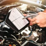 Auto mechanic hand is blowing dust and cleaning a car air filter with air blow gun in tha auto repair garage