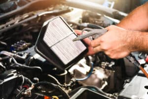 Auto mechanic hand is blowing dust and cleaning a car air filter with air blow gun in tha auto repair garage