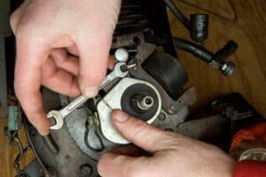Mechanic adjusts ignition coil on small petrol engine lawn mower.