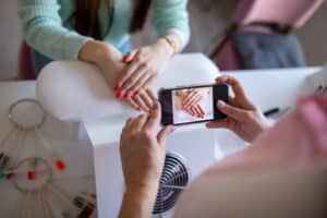 Nail salon worker taking photos of her customers nails with a smart phone