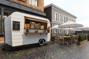 Close up of a snack van with wooden tables and chairs.
