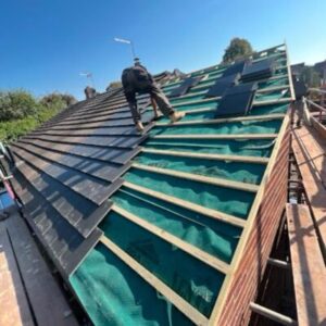 A roofer laying down batons for tiles to be laid on the roof.